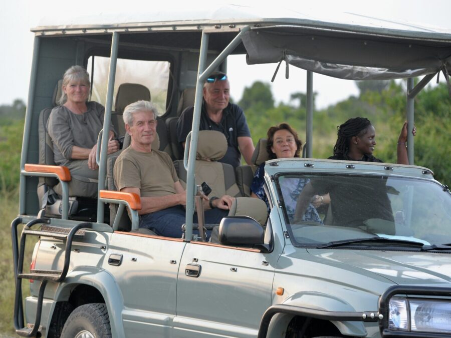 Safari guests travelling in an open roof four wheel drive vehicle
